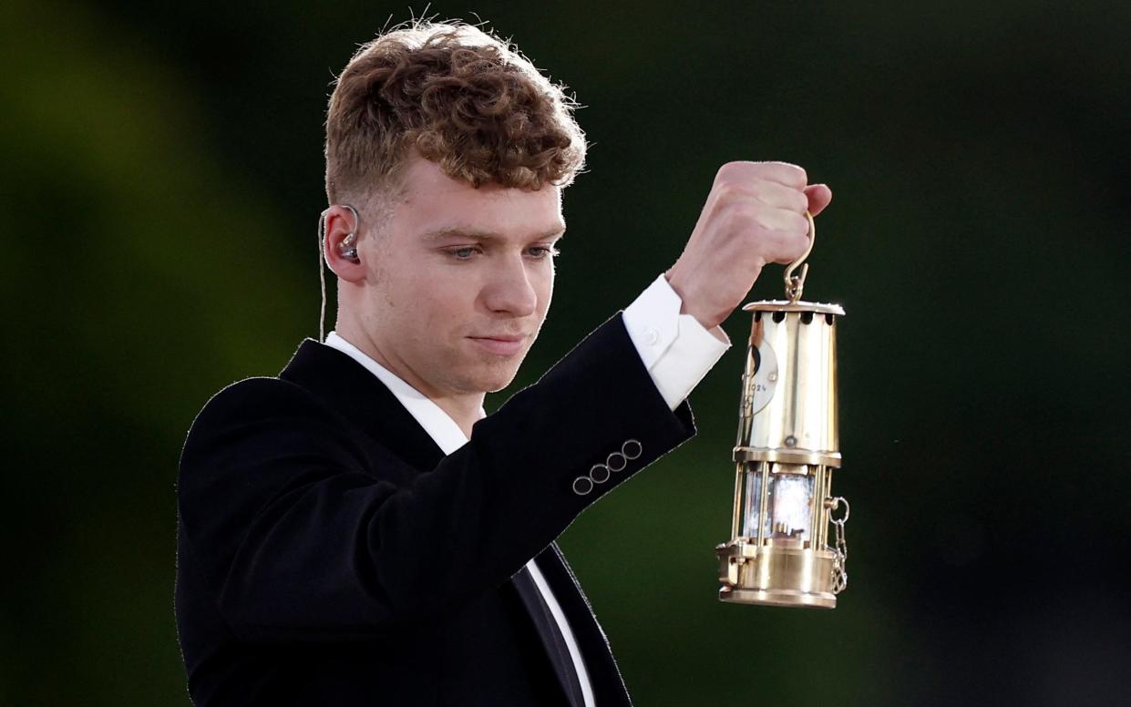 Leon Marchand carries the Olympic flame.