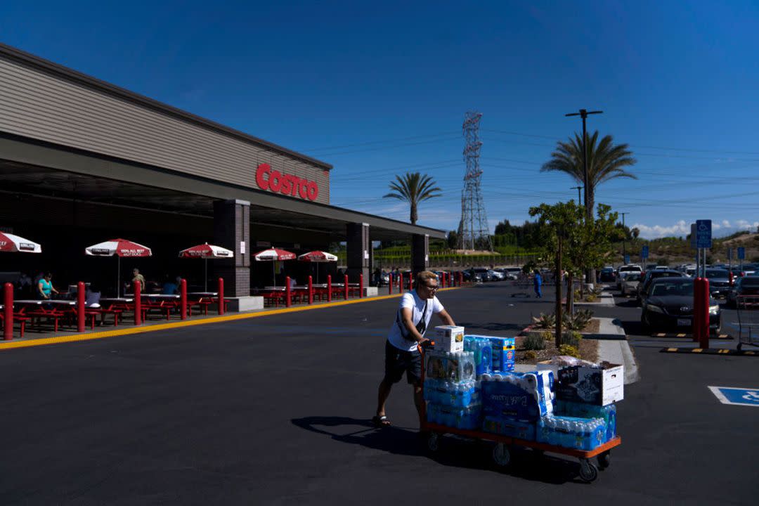 Customer leaving Costco with shopping cart full of water bottles