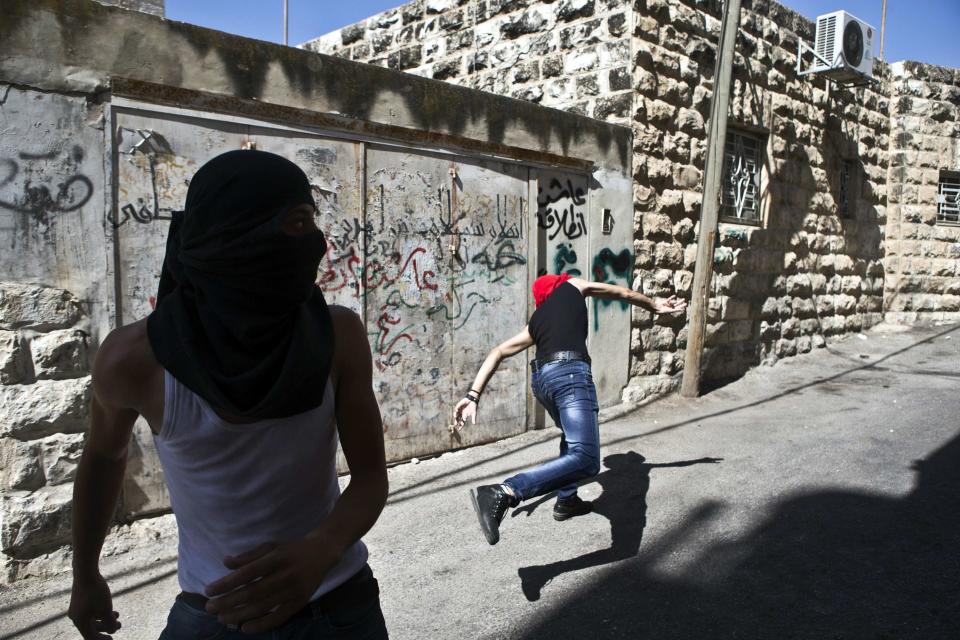 Palestinian youth throws a stone during clashes with Israeli police following Friday prayers in East Jerusalem