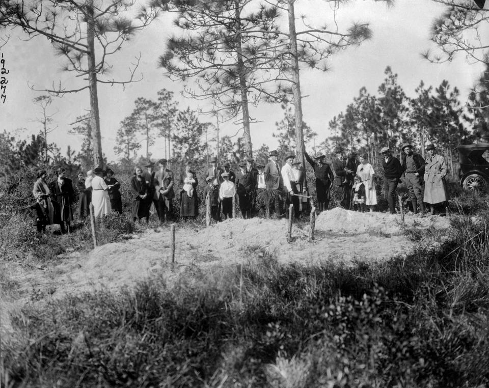 White residents of Sumner stand near three graves of six Black victims who were killed in Rosewood.<span class="copyright">Bettmann Archive/Getty Images</span>