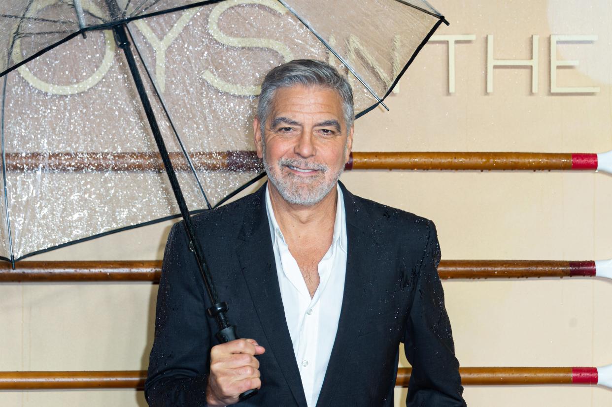 George Clooney holding an umbrella and smiling