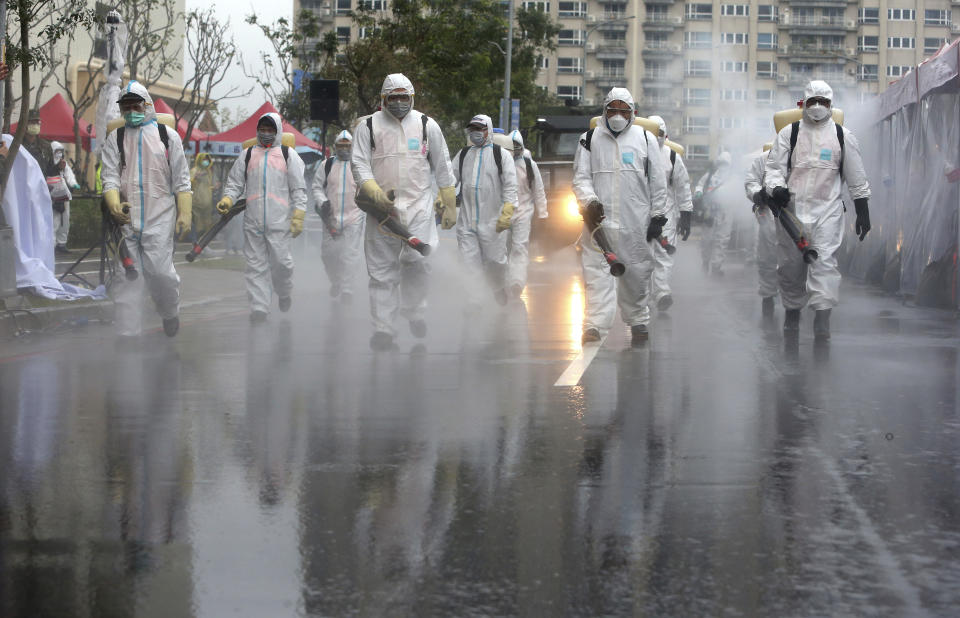 FILE - In this March 14, 2020, file photo Taiwanese army soldiers wearing protective suits spray disinfectant over a road during a drill to prevent community cluster infection of coronavirus in New Taipei City, Taiwan. The administration, backed by a bipartisan collection of lawmakers, is pressing for Taiwan's inclusion as a separate entity in international organizations like the World Health Organization and the International Civil Aviation Organization, both of which have significant roles in anti-virus efforts. (AP Photo/Chiang Ying-ying, File)