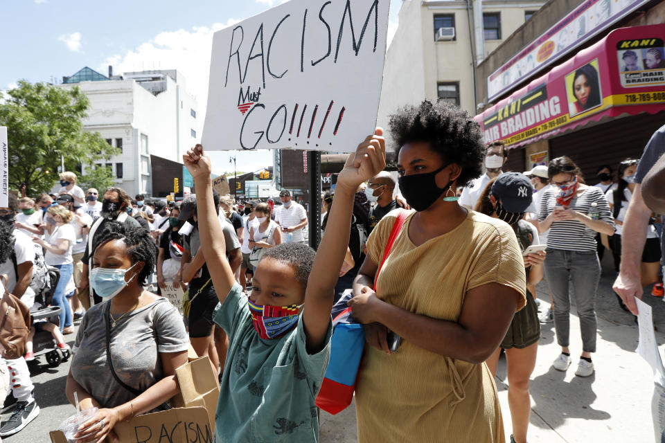 Joshua Wright, 8, holds a sign as he stands with his mother, left, and Chrystalle Henry, during a Pray & Protest rally and march, Sunday, June 7, 2020, in the Bedford-Stuyvesant neighborhood of the Brooklyn borough of New York. (AP Photo/Kathy Willens)