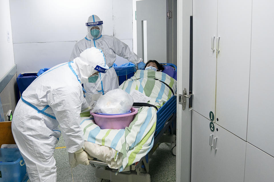 Medical workers transfer a patient out of the intensive care unit at hospital in Wuhan. Source: AP