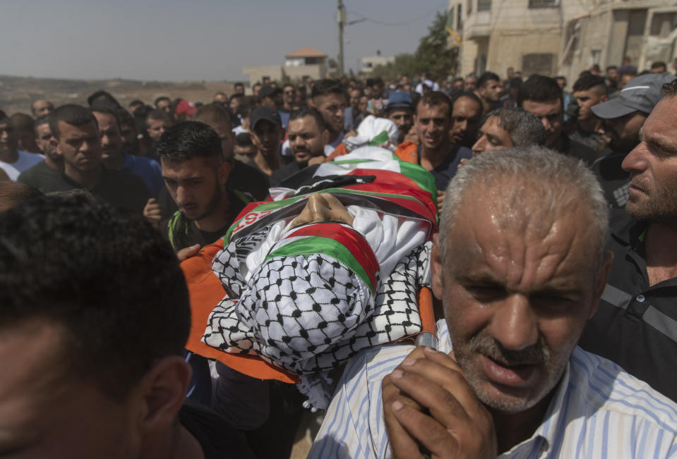 Palestinian mourners carry the body of Shaukat Awad, 20 during his funeral in the West Bank village of Beit Ummar, near Hebron, Friday, July. 30, 2021. Israeli troops shot and killed the 20 year old Palestinian man, Palestinian health officials said, during clashes that erupted in the occupied West Bank following the funeral of a Palestinian boy killed by army fire the previous day. (AP Photo/Nasser Nasser)