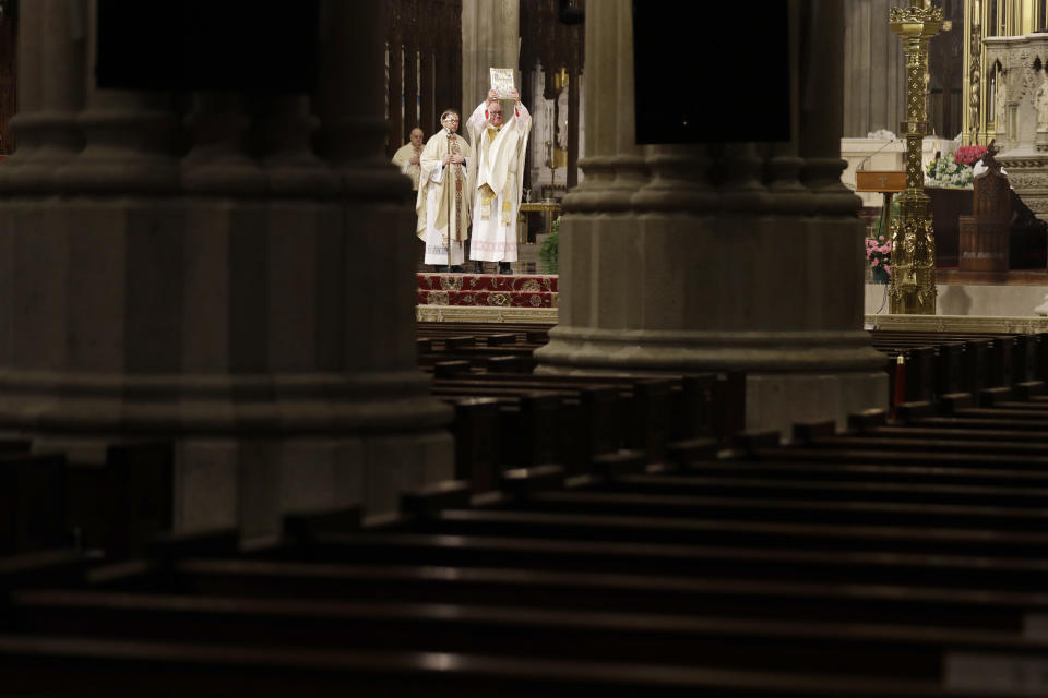 Archbishop Timothy Dolan, right, leads an Easter Mass at St. Patrick's Cathedral, devoid of congregants, in New York, Sunday, April 12, 2020. Due to coronavirus concerns, no congregants were allowed to attend the Mass but it was broadcast live on a local TV station. (AP Photo/Seth Wenig)