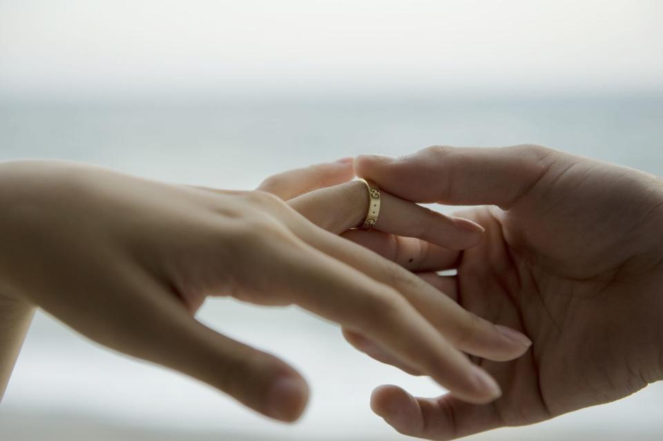 man takes wedding ring of woman's hand