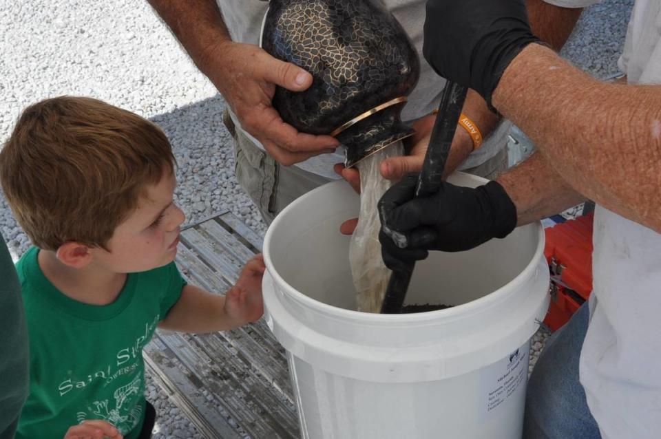 A family mixes the cremated remains of a loved one with concrete to form the “pearl” that will be placed at the center of a reef ball before it is lowered underwater.