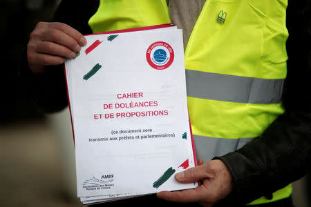 FILE PHOTO: A yellow vests movement member holds a book of grievances (in French "Cahier de doleances") in Flagy, France, January 9, 2019. Picture taken January 9, 2019. REUTERS/Benoit Tessier/File Photo