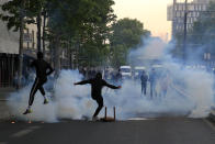 Protester kick in tear gas canisters during a demonstration Tuesday, June 2, 2020 in Paris. Thousands of people defied a police ban and converged on the main Paris courthouse for a demonstration to show solidarity with U.S. protesters and denounce the death of a black man in French police custody. The demonstration was organized to honor Frenchman Adama Traore, who died shortly after his arrest in 2016, and in solidarity with Americans demonstrating against George Floyd's death. (AP Photo/Michel Euler)