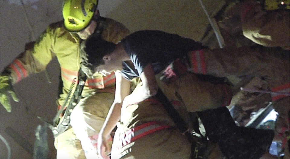 This photo taken from video provided by ReliableNewsMedia firefighters rescue a survivor from the rubble of the Champlain Towers South Condo after the multistory building partially collapsed in Surfside, Fla., early Thursday, June 24, 2021. (ReliableNewsMedia via AP).