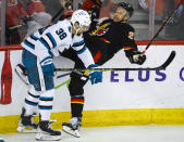 San Jose Sharks defenseman Mario Ferraro, left, checks Calgary Flames forward Trevor Lewis during the first period of an NHL hockey game in Calgary, Alberta, Saturday, March 25, 2023.(Jeff McIntosh/The Canadian Press via AP)