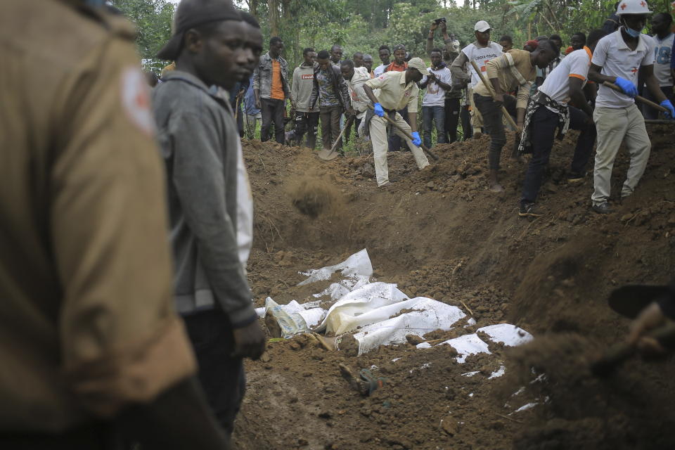 Red Cross volunteers bury the remains of civilians killed in the Democratic Republic of Congo North Kivu province village of Mukondi, Thursday March 9, 2023. At least 36 were killed when the Allied Democratic Forces, a group with links to the Islamic State group, attacked the village and burned residents' huts. (AP Photo/Socrate Mumbere)