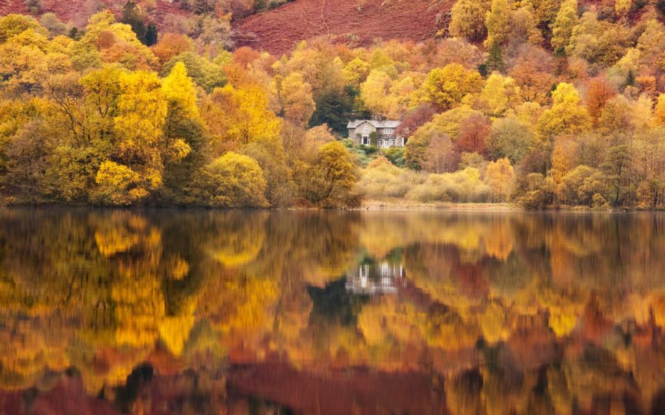 Still lakeside reflections at Grasmere in the Lake District, Cumbria, England, UK - Getty