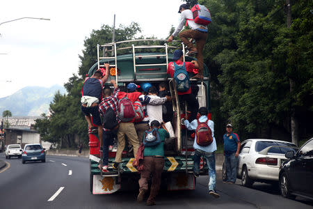 Honduran migrants, part of a caravan trying to reach the U.S., climb on a bus during a new leg of their travel, in Guatemala City, Guatemala October 18, 2018. REUTERS/Edgard Garrido