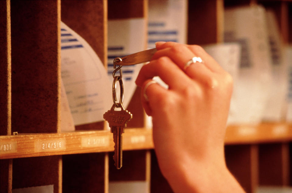 Person retrieving a key from numbered hotel key slots