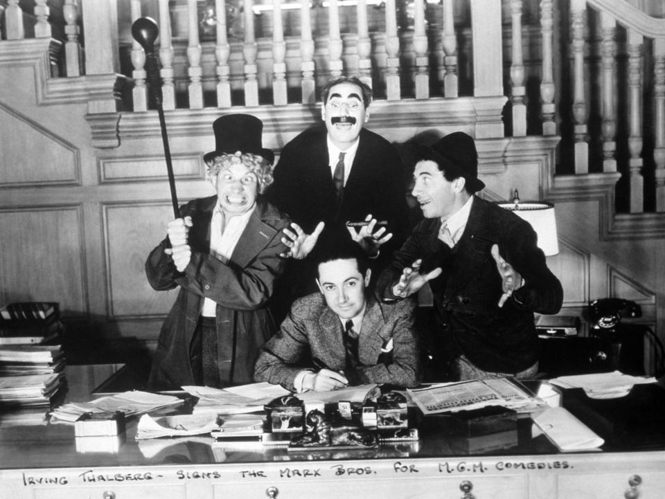 The Marx Brothers signing with Irving Thalberg for MGM Studios in 1935, with a copy of <em>The Hollywood Reporter</em> sitting on the studio mogul’s desk.