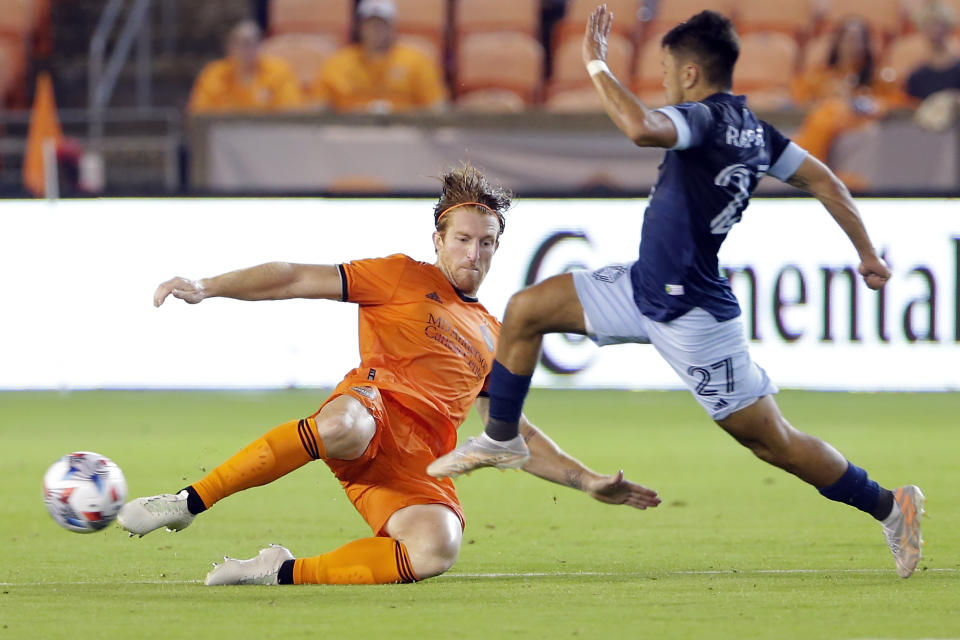 Houston Dynamo defender Tim Parker, left, attempts to kick away the ball as Vancouver Whitecaps midfielder Ryan Raposo (27) moves to the goal during the second half of an MLS soccer match Saturday, May 22, 2021, in Houston. (AP Photo/Michael Wyke)