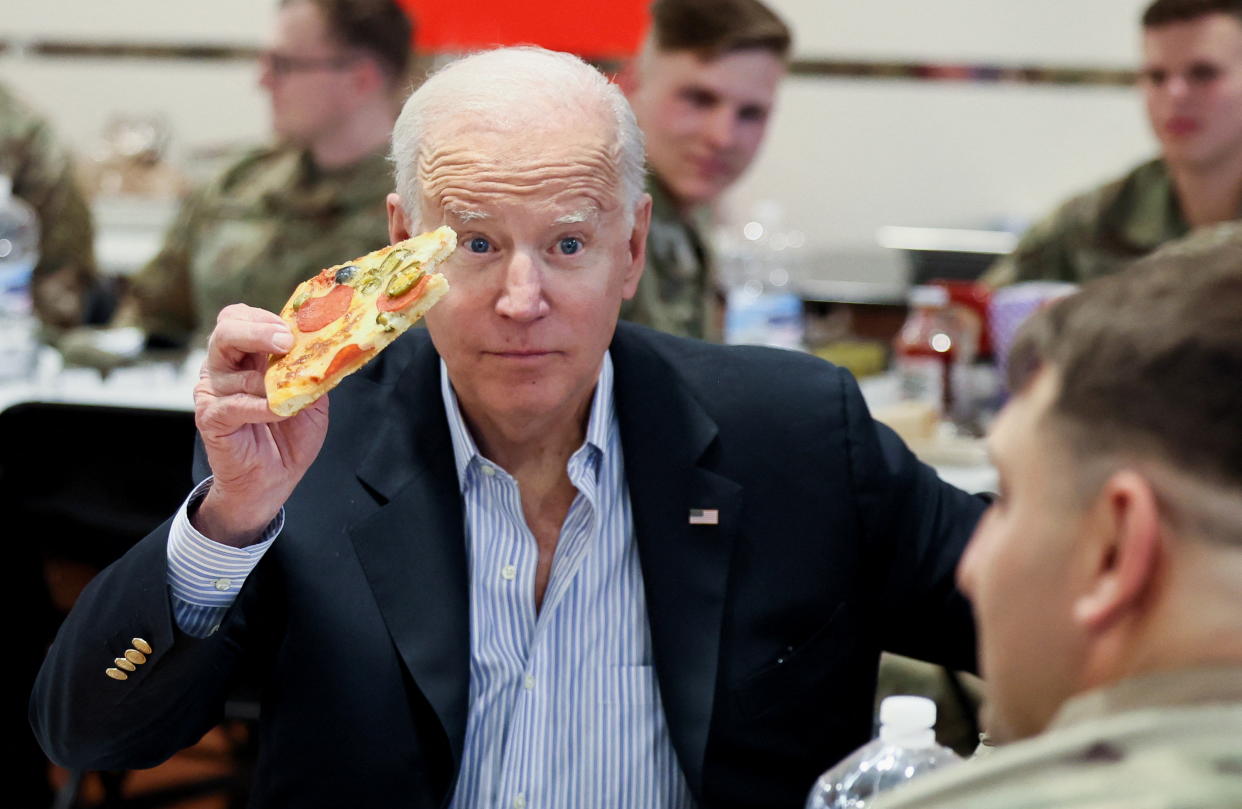 U.S. President Joe Biden eats pizza as he meets with U.S. Army soldiers assigned to the 82nd Airborne Division at the G2 Arena in Jasionka, near Rzeszow, Poland, March 25, 2022. REUTERS/Evelyn Hockstein