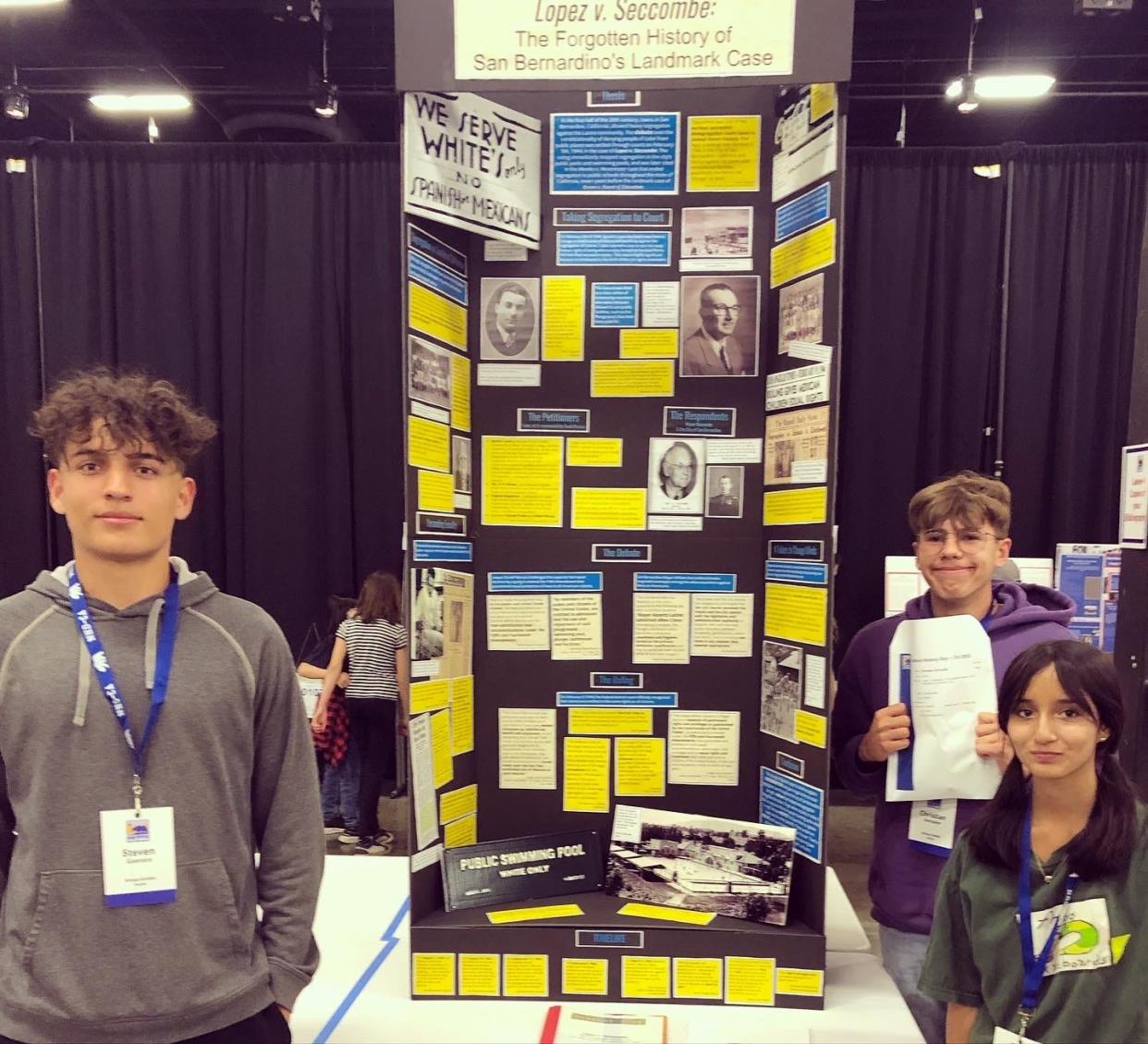 Oak Hills High School students Steven Guevara, Christian Gonzalez and Christina Godinez stand in front of their exhibit highlighting a civil rights case from San Bernardino County. The three students are finalists in the National History Day National Contest.