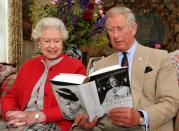 The Queen and Prince Charles with a copy of <em>Queen Elizabeth, The Queen Mother: The Official Biography</em> at Birkhall, on the Balmoral Estate.