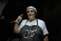 Jinane Hayek, who lost her job as a branch manager at one of the largest banks in Lebanon two years ago, speaks during an interview with the Associated Press at her own bakery in Bekfaya town, in the Mount Lebanon governorate, Lebanon, Friday, Sept. 23, 2022. Hayek worked in Lebanon's banking sector for nearly three decades but lost her job after the country's economic meltdown began. The Arabic on the apron reads: "Women of bakery." (AP Photo/Bilal Hussein)