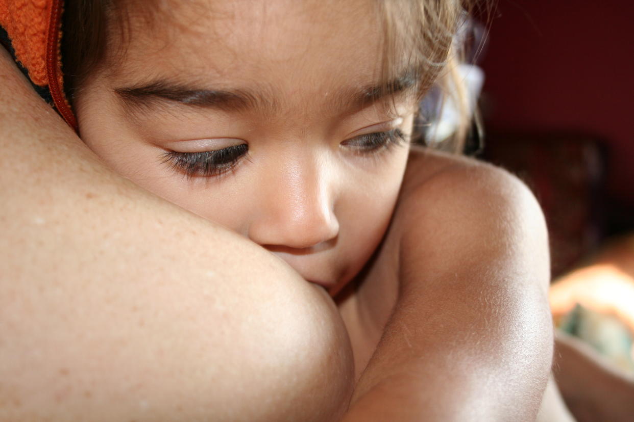 A baby girl breast feeds her mother at nap time.