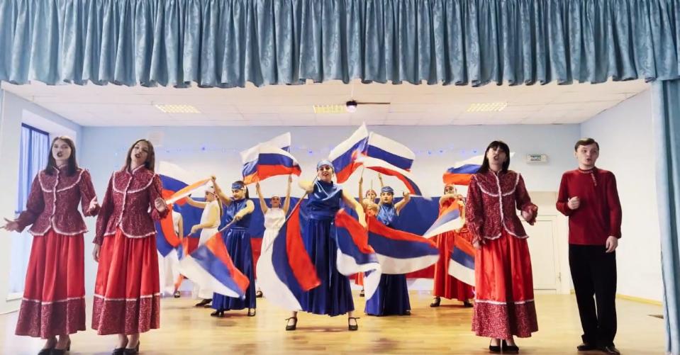 A Russian propaganda lesson featuring students dancing with Russian flags.