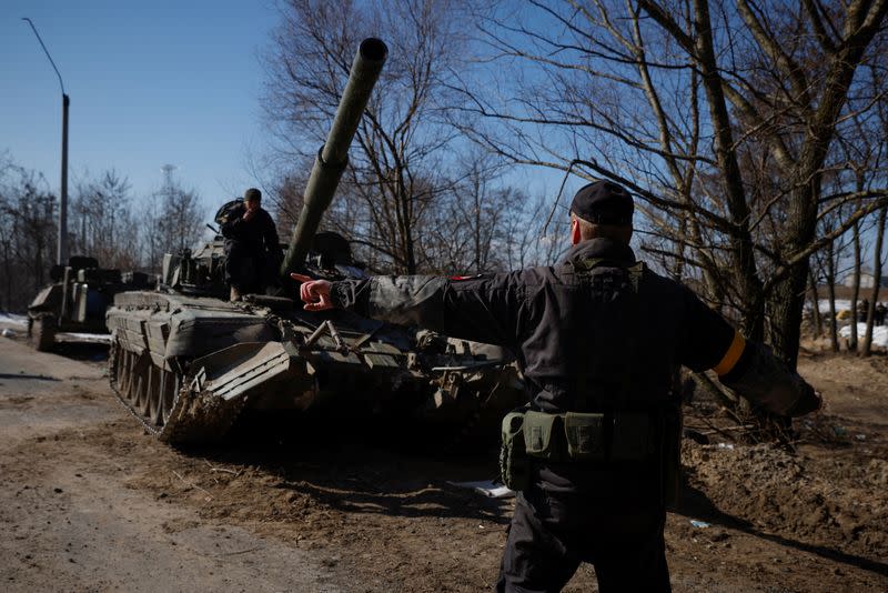 A Ukrainian soldier directs a Russian tank that Ukrainians captured after fighting with Russian troops, as Russia's attack on Ukraine continues, outside Brovary