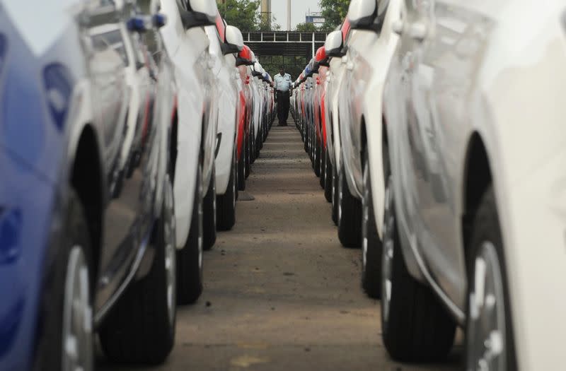 Employee walks between parked Hyundai cars ready for shipment at a port in the southern Indian city of Chennai