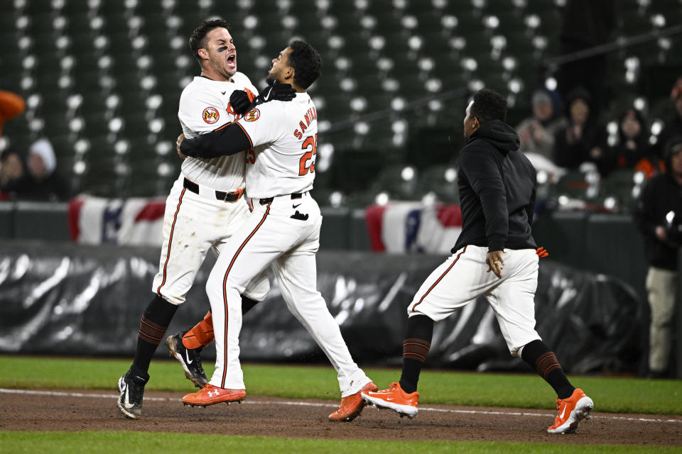 Baltimore Orioles' James McCann, left, celebrates with Anthony Santander, center, after McCann hit a walk-off single that drove in two runs during the ninth inning of a baseball game against the Kansas City Royals, Wednesday, April 3, 2024, in Baltimore. The Orioles won 4-3. (AP Photo/Nick Wass)