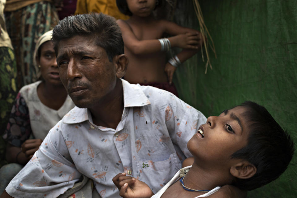 SITTWE, BURMA - MAY 06: Roshida Moud, 12, is held by his father as he explains that his son was hit in the head with a stone during the Rakhine violence in 2012. Roshida Moud has been unable to function by himself since the inury.150,000 Rohingya IDP (internally displaced people) are currently imprisoned in refugee camps outside of Sittwe in Rakhine State in Western Myanmar. Medecins Sans Frontieres (MSF), the primary supplier of medical care within the camps, was banned in March by the Myanmar government. Follow up attacks by Buddhist mobs on the homes of aid workers in Sittwe put an end to NGO operations in the camps. Though some NGOs are beginning to resume work, MSF remains banned, and little to no healthcare is being provided to most Rohingya IDPs. One Rohingya doctor is servicing 150,000 refugees with limited medication. Several Rakhine volunteer doctors sporadically enter the camps for two hours a day. Births are the most complicated procedures successfully carried out in the camps, requests to visit Yangon or Sittwe hospitals for life threatening situations require lengthy applications and are routinely denied. Malnutrition and diarrhea are the most widespread issues, but more serious diseases like tuberculosis are going untreated and could lead to the rise of drug resistant tuberculosis (DR-TB).  (Photo by Andre Malerba/Getty Images)