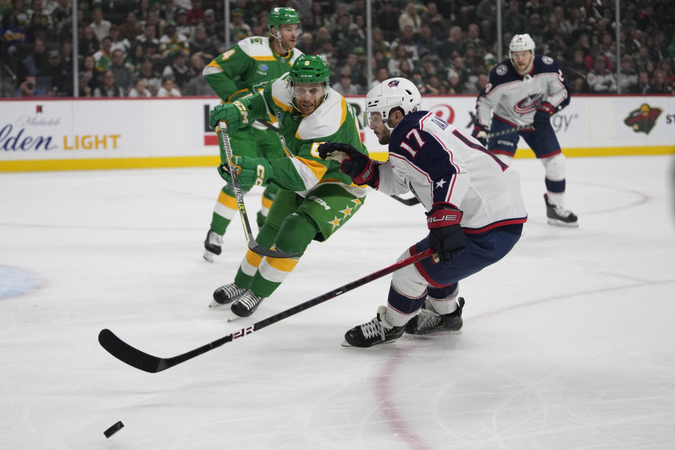 Minnesota Wild defenseman Dakota Mermis, front left, and Columbus Blue Jackets right wing Justin Danforth (17) battle for the puck during the first period of an NHL hockey game Saturday, Oct. 21, 2023, in St. Paul, Minn. (AP Photo/Abbie Parr)