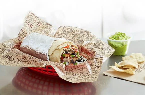 Chipotle burrito with a side of guacamole and chips.