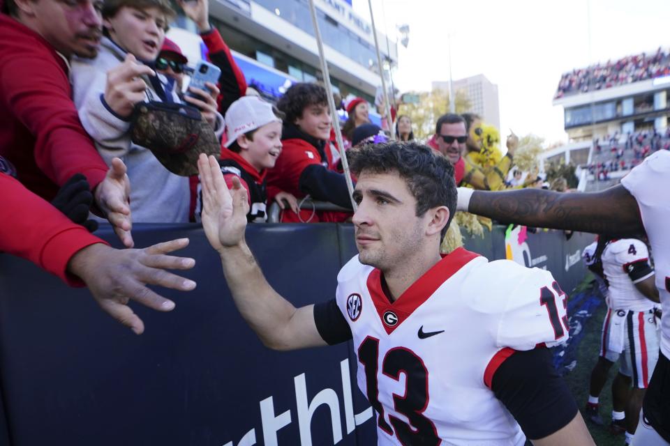 Georgia quarterback Stetson Bennett (13), seen here celebrating with fans after beating Georgia Tech last week, is an underappreciated player and leads the nation in several important stat categories. The former walk-on has kept the job over the much-hyped JT Daniels.