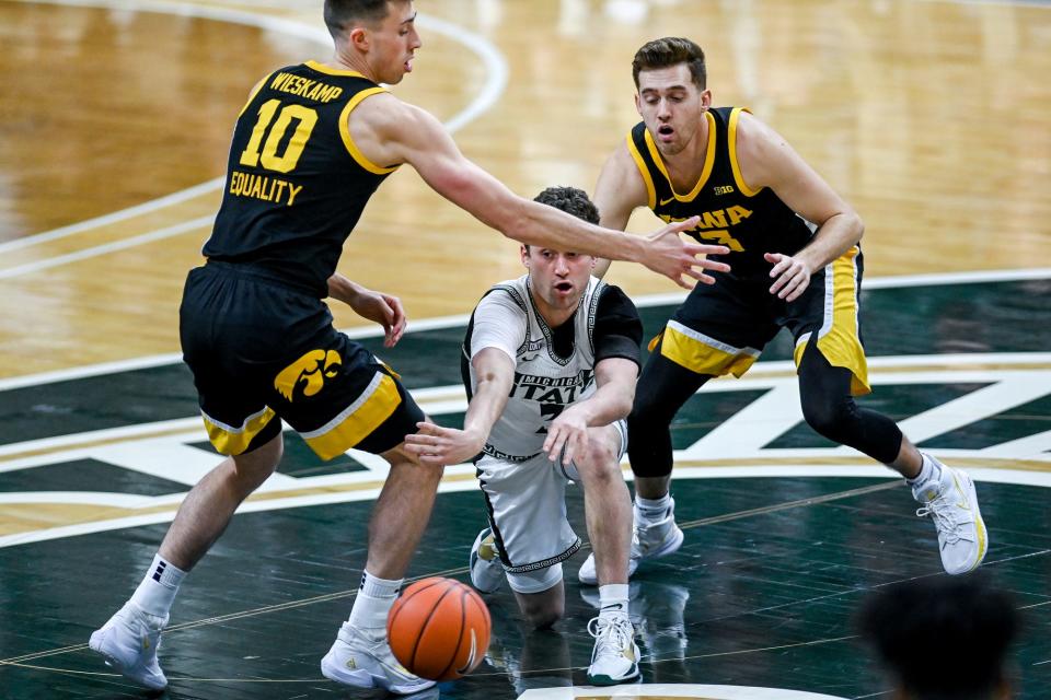 Michigan State's Foster Loyer, center, passes the ball between Iowa's Joe Wieskamp, left, and Jordan Bohannon during the first half on Saturday, Feb. 13, 2021, at the Breslin Center in East Lansing.