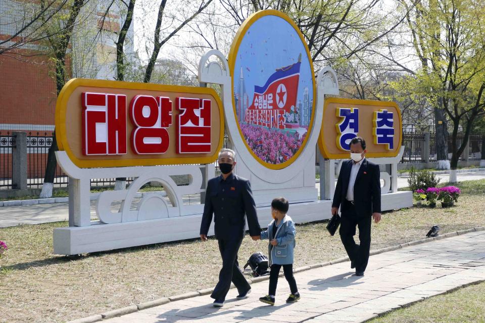 People walk in the street decorated with posters marking the 110th birth anniversary of late state founder Kim Il Sung, in Pyongyang, North Korea Friday, April 15, 2022. The poster says "The leader is father of the socialist Korea!" (AP Photo/Jon Chol Jin)