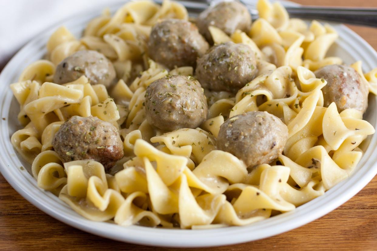 Beef stroganoff made with meatballs on a white plate and wooden table.