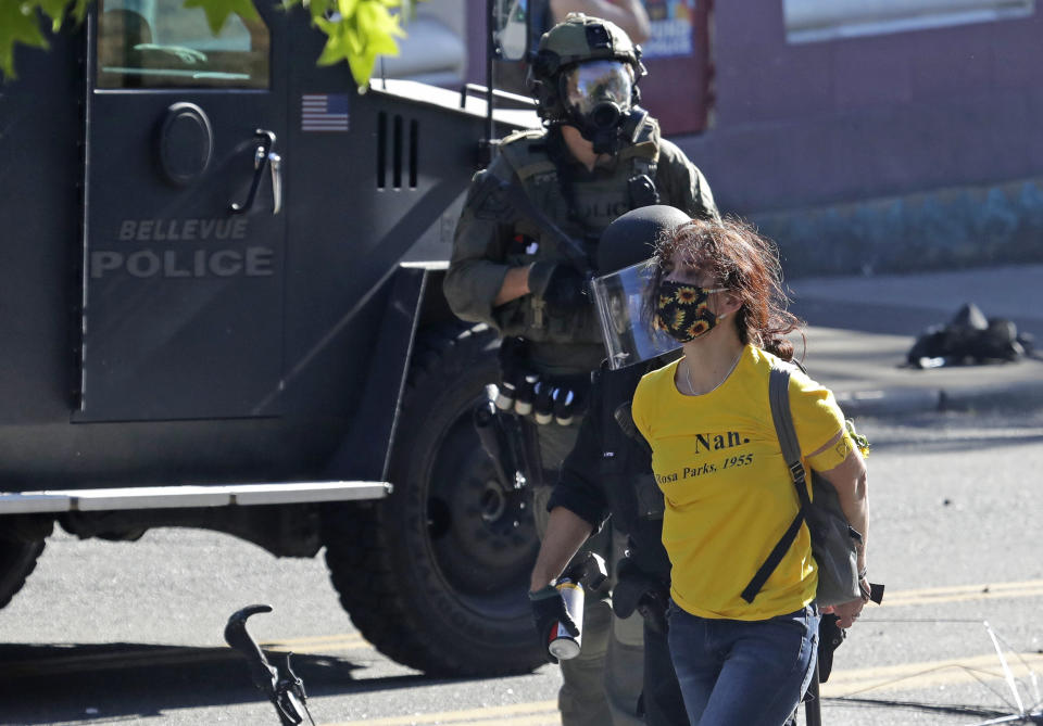 Police arrest a person wearing a yellow shirt an armband that reads "Mom," Saturday, July 25, 2020, during a Black Lives Matter protest near Seattle Central Community College in Seattle. A large group of protesters were marching Saturday in Seattle in support of Black Lives Matter and against police brutality and racial injustice. (AP Photo/Ted S. Warren)