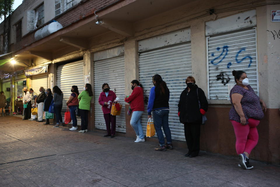 People line up for a free dinner at a soup kitchen in Mexico City, Saturday, Dec. 19, 2020, amid the COVID-19 pandemic. This soup kitchen is operated by neighbors who are in charge of preparing food and serving it to the public for free. The Secretariat of Inclusion and Social Welfare of Mexico City started its soup kitchen program in 2009. (AP Photo/Ginnette Riquelme)