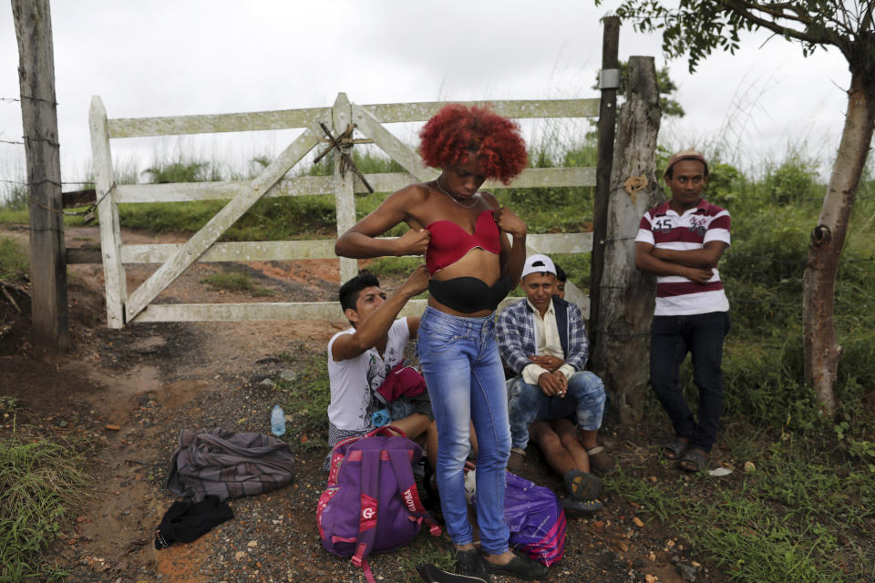 In this Nov. 3, 2018 photo, Honduran transgender Alexa Amaya, who is traveling with the migrant caravan hoping to reach the U.S. border, tries on a pushup bra she selected from a pile of donated clothing left alongside the road to Sayula, Mexico. Fleeing violence and discrimination back home because of their gender identity or sexual orientation, about 50 LGBTQ migrants, including Alexa, have found the journey north to be just as threatening and have banded together for protection against mistreatment from their fellow travelers. (AP Photo/Rodrigo Abd)