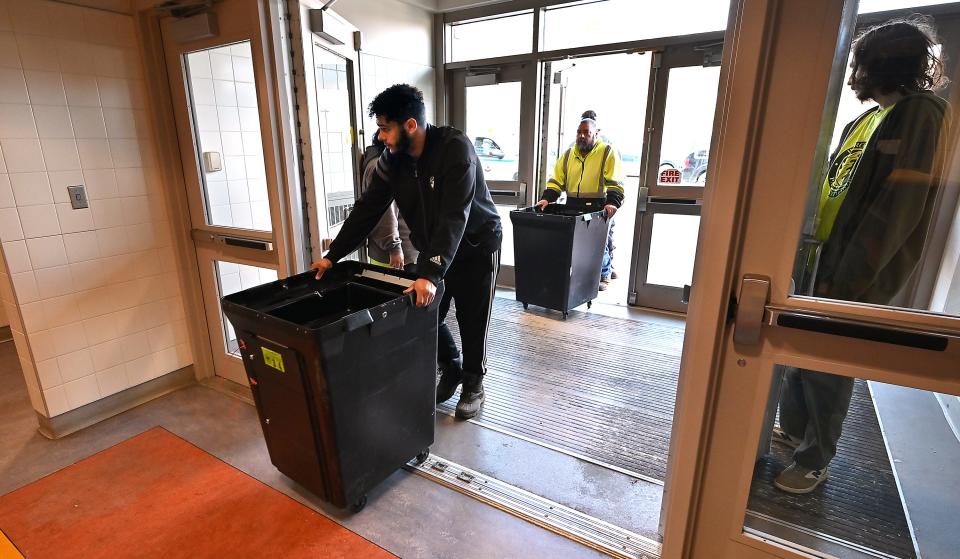City workers Michael Rossi and Fred Vickers, back, roll in ballot boxes as they help set up polls at Worcester Technical High School Monday.