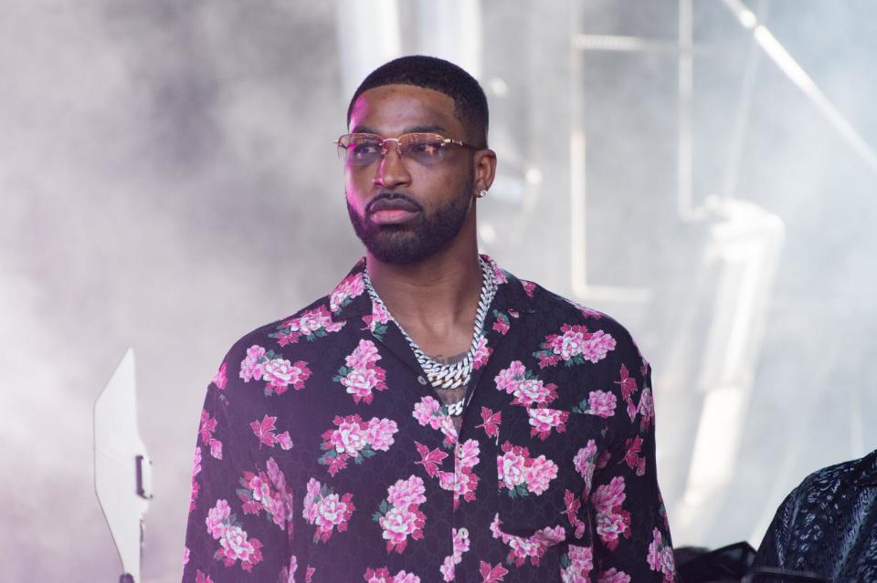 Tristan Thompson wears a chain and floral shirt while watching a concert from the wings