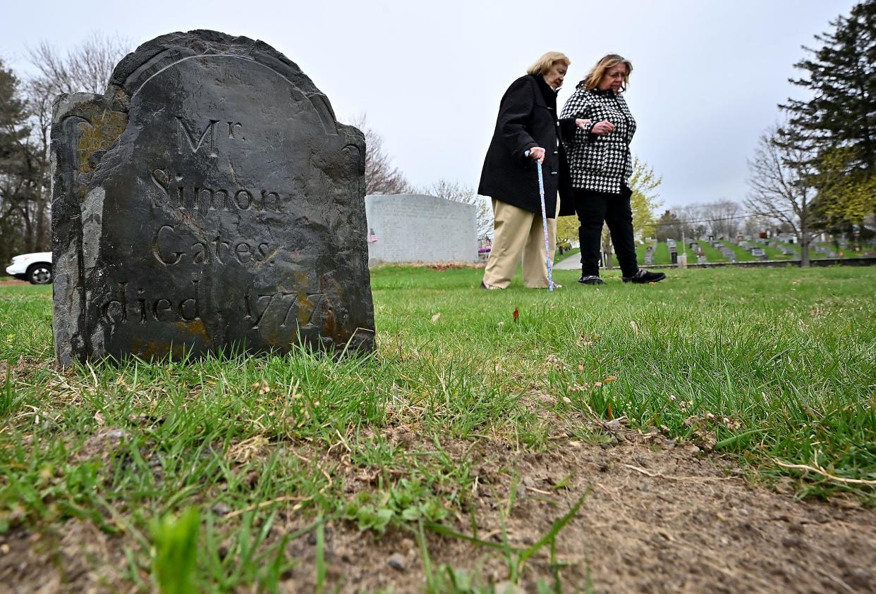 Janet Parent assists Cookie Nelson after they visited two of the gravestones from the 1700s that were unearthed at Hope Cemetery.