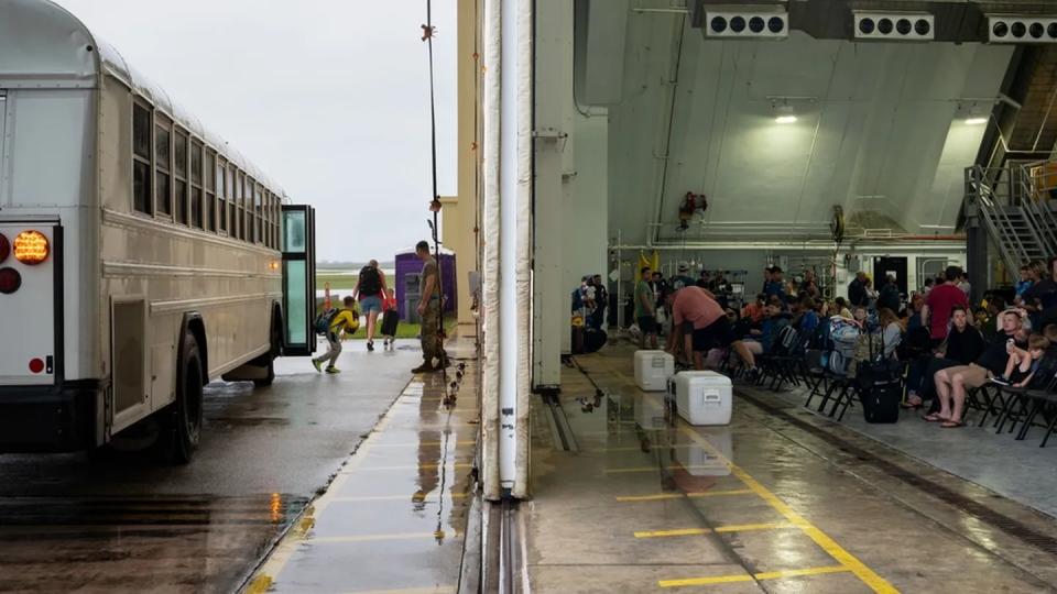 Outbound airmen and their families are transported to Hangar 1 on Andersen Air Force Base, Guam, May 30. Typhoon Mawar caused significant damage to the 734th Air Mobility Squadron's passenger terminal. With the terminal out of commission, the 734th AMS teamed up with the 4th Reconnaissance Squadron and are now using their hangar as a temporary terminal until repairs to the main facility are complete. (Staff Sgt. Pedro Tenorio/Air Force)