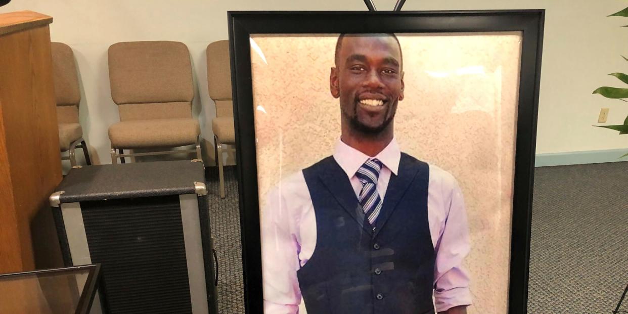 A portrait of Tyre Nichols, a Black man wearing a suit, in a black frame