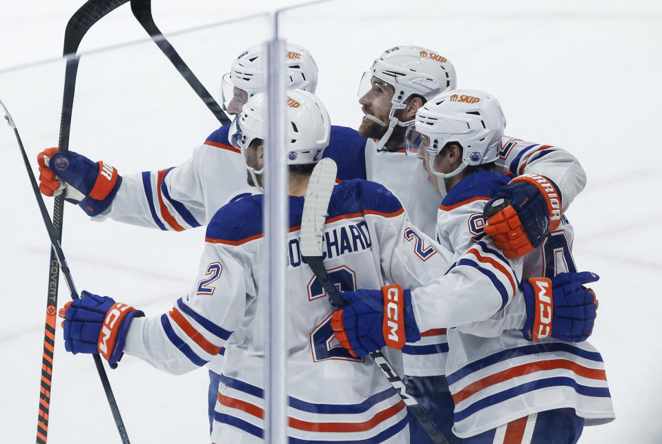 Edmonton Oilers' Zach Hyman (18), Evan Bouchard (2), Leon Draisaitl (29) and Ryan Nugent-Hopkins (93) celebrate Draisaitl's goal against Winnipeg Jets goaltender Connor Hellebuyck during the third period of an NHL hockey game Thursday, Nov 30, 2023, in Winnipeg, Manitoba. (John Woods/The Canadian Press via AP)