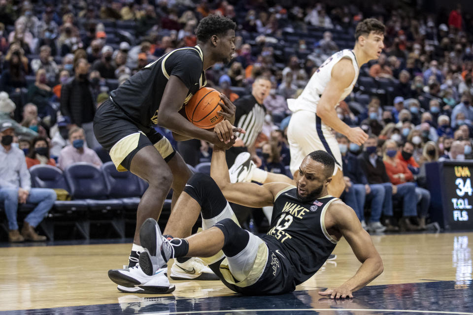 Wake Forest forward Khadim Sy (20) helps up forward Dallas Walton (13) during the second half of an NCAA college basketball game against Virginia in Charlottesville, Va., Saturday, Jan. 15, 2022. (AP Photo/Erin Edgerton)