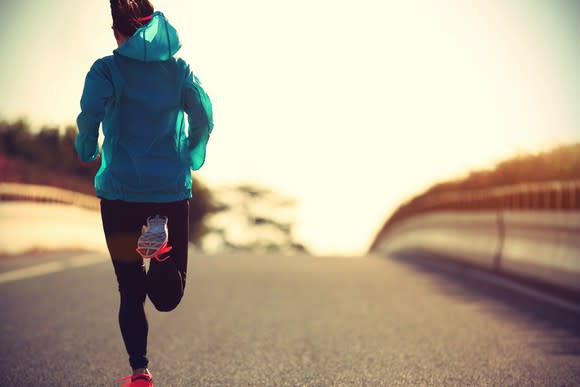 A woman in fitness gear running down a road.