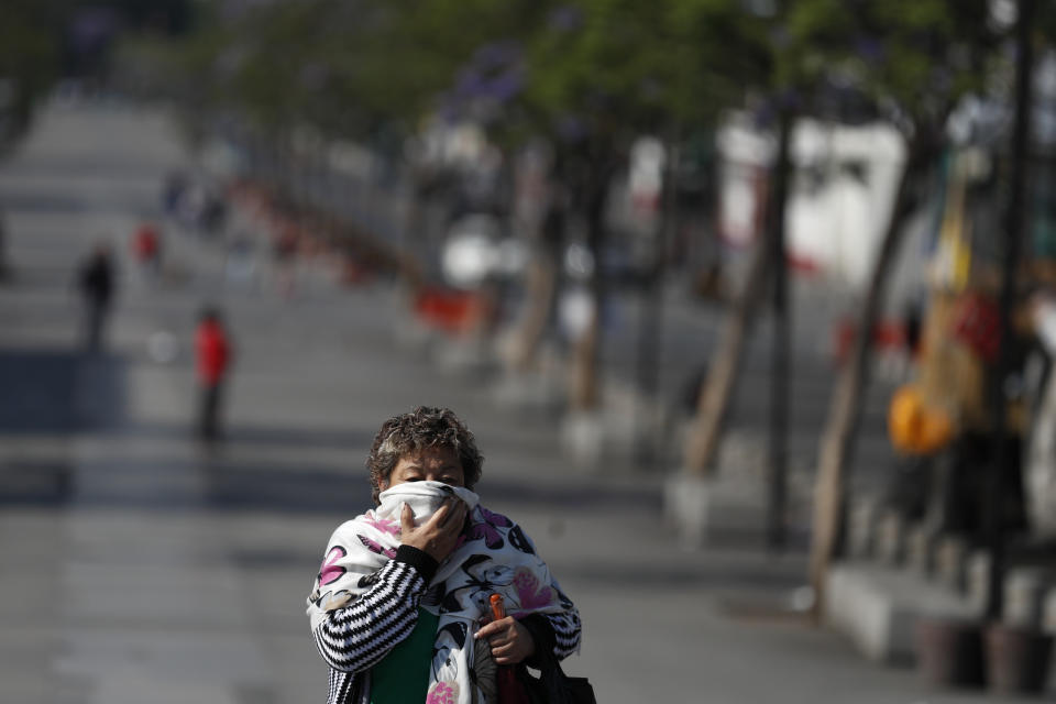 A woman wearing a scarf over her face walks up the nearly empty boulevard leading to the Basilica of Our Lady of Guadalupe, which was closed to the public to prevent the spread of coronavirus, in Mexico City, on Good Friday, April 10, 2020. Instead of celebrating with the usual packed churches and elaborate processions attended by thousands, this year, Mexico's Catholic faithful were told to stay home, with closed-door Masses and a private performance of the Stations of the Cross broadcast on television.(AP Photo/Rebecca Blackwell)